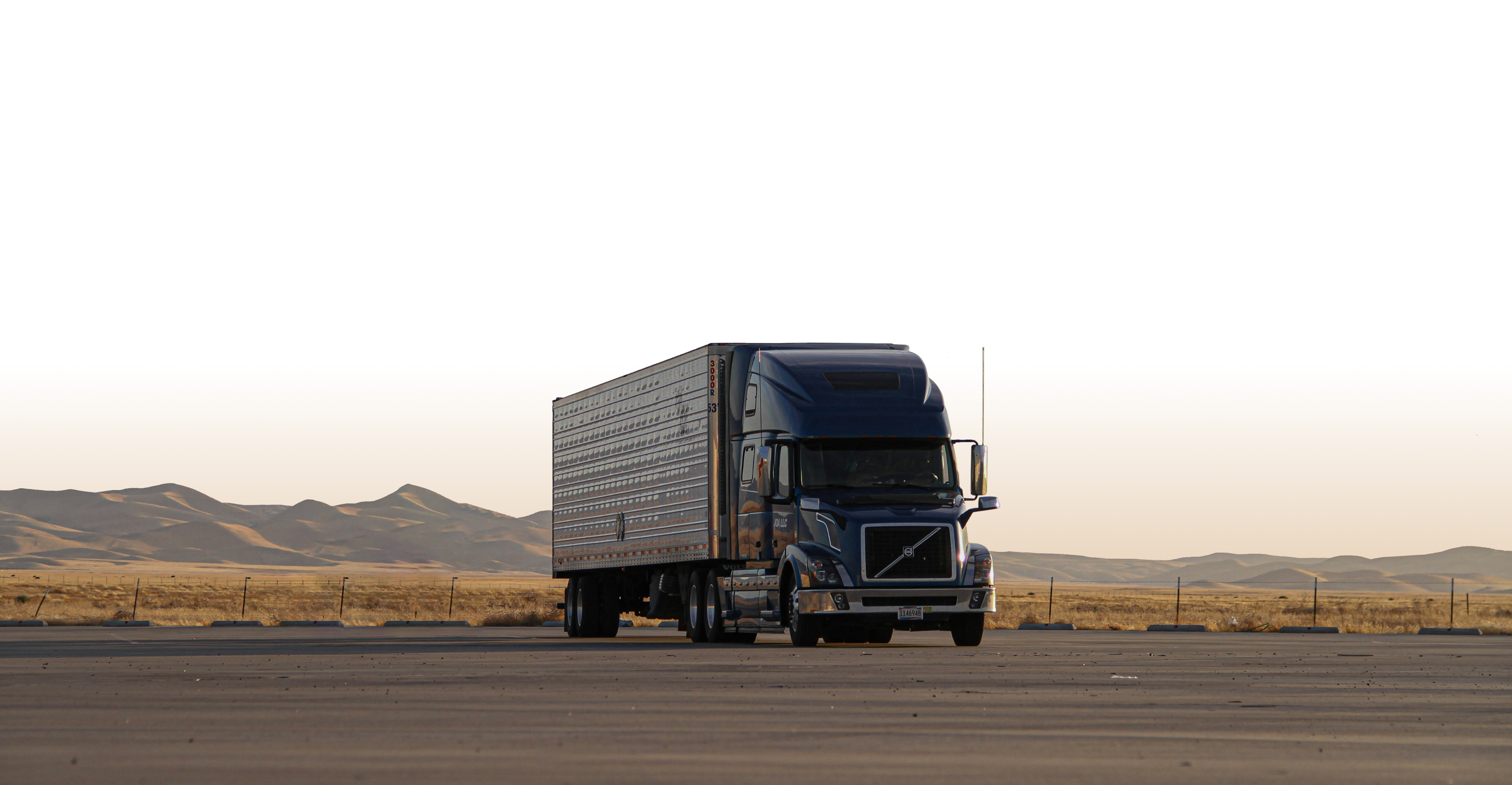 A dark blue logistics truck parked in a wide desert landscape